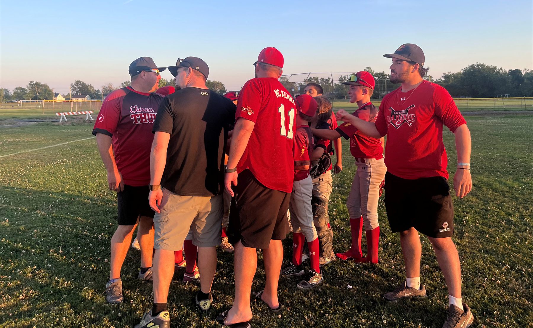 Coaches and players in a golden-hour huddle after a game